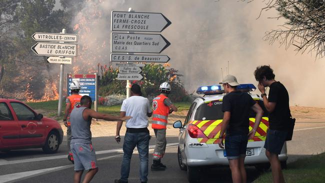 People stand by emergency workers as a fire which has already devastated some 200 hectares approaches Vitrolles, southern France. Picture: AP