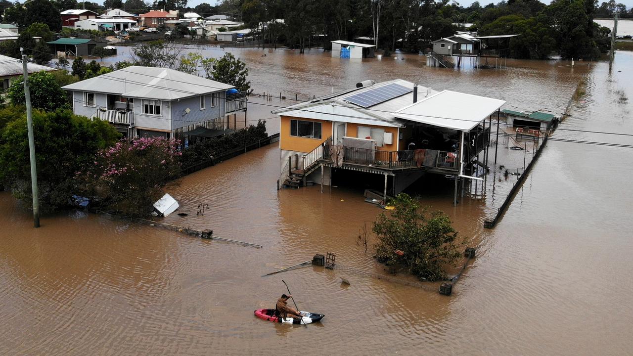 A Coraki resident paddles his kayak out of his waterlogged house on Grenfell St. Picture: Toby Zerna