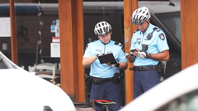 The officers pause to write up a ticket. Picture: David Crosling