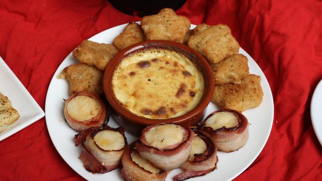 The Coles Welsh rarebit Chees Bake, with Aldi’s maple bacon wrapped scallops and Christmas Fig Parmesan &amp; Cheddar Bites from Coles. Picture: Liam Kidston