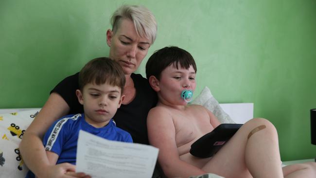 Gold Coast mother Shannon Manning reads a letter from the NDIS with her disabled children Madden 6, (left) and Meadow 7 at their Maudsland home. Picture Glenn Hampson