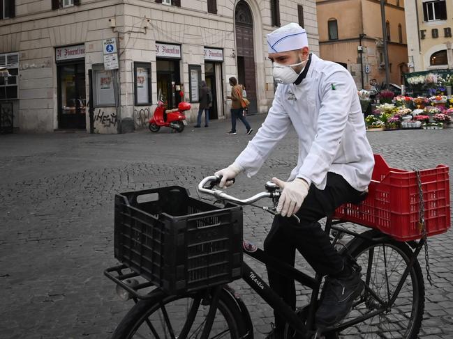 A cook rides a bicycle across a deserted Campo Dei Fiori square in Rome. Picture: AFP