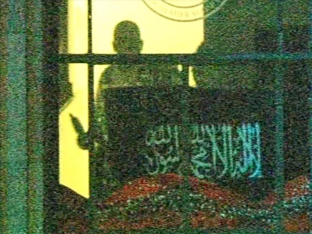 12. Man Monis is sighted through the window with a sawn-off pump action shotgun in his right hand. threatening the hostages as darkness falls.