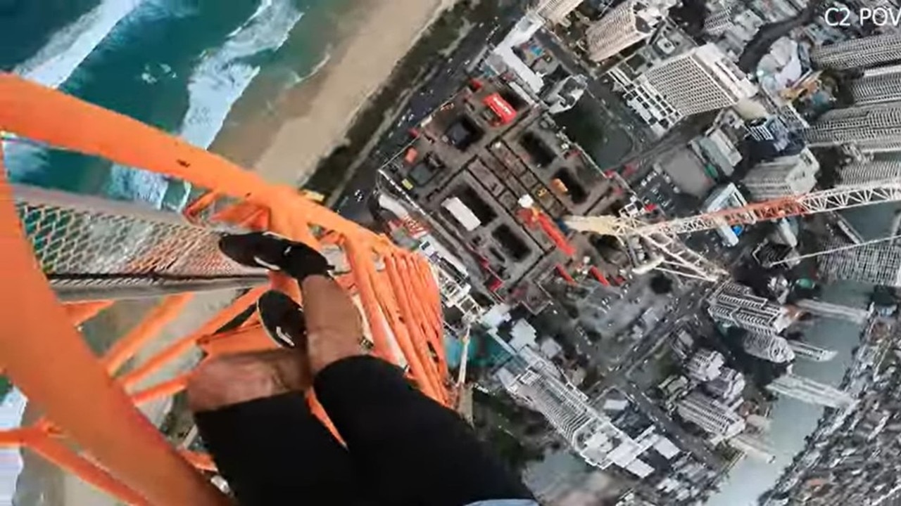 A video has emerged online of a man dangling from the top of a crane at Surfers Paradise, with police warning against the dangerous behaviour.