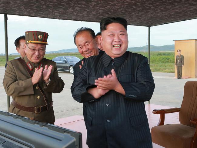 North Korean leader Kim Jong Un, right, celebrates what was said to be the test launch of an intermediate range Hwasong-12 missile at an undisclosed location. Picture: AP