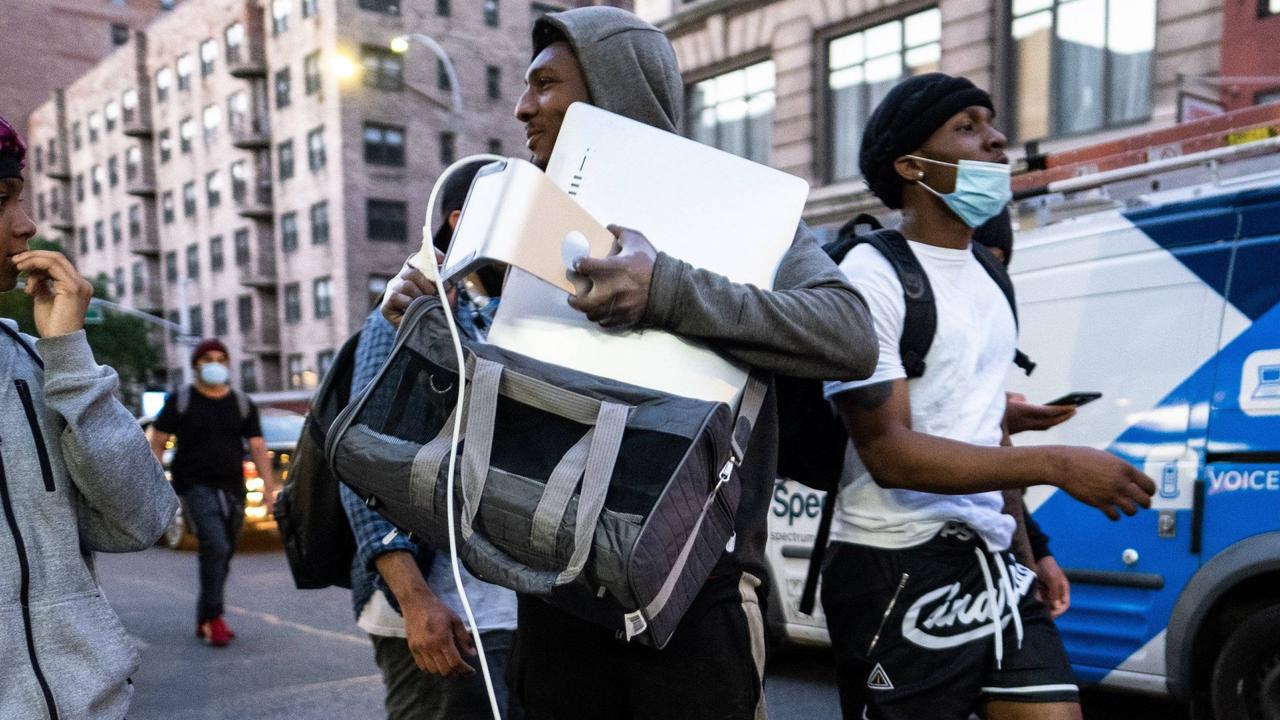 An alleged looter tries to fit an Apple iMac in his bag. Picture: Stephen Yang / MEGA