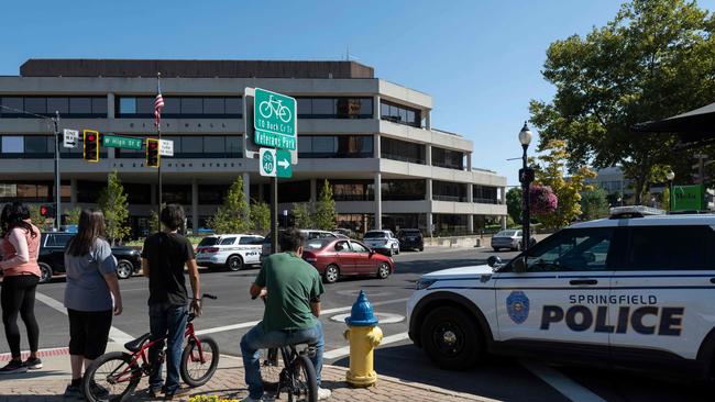 People watch as Springfield Police Department officers investigate the Springfield City Hall after bomb threats were made against buildings earlier in the day. (Photo by ROBERTO SCHMIDT / AFP)