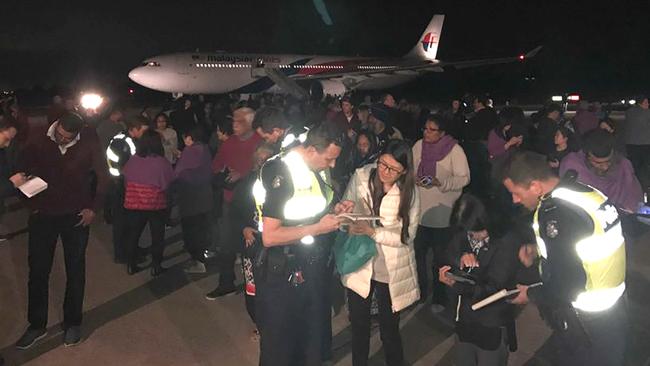 Passengers speaking to officers on the tarmac after coming off the Malaysia Airlines flight. Picture: AFP
