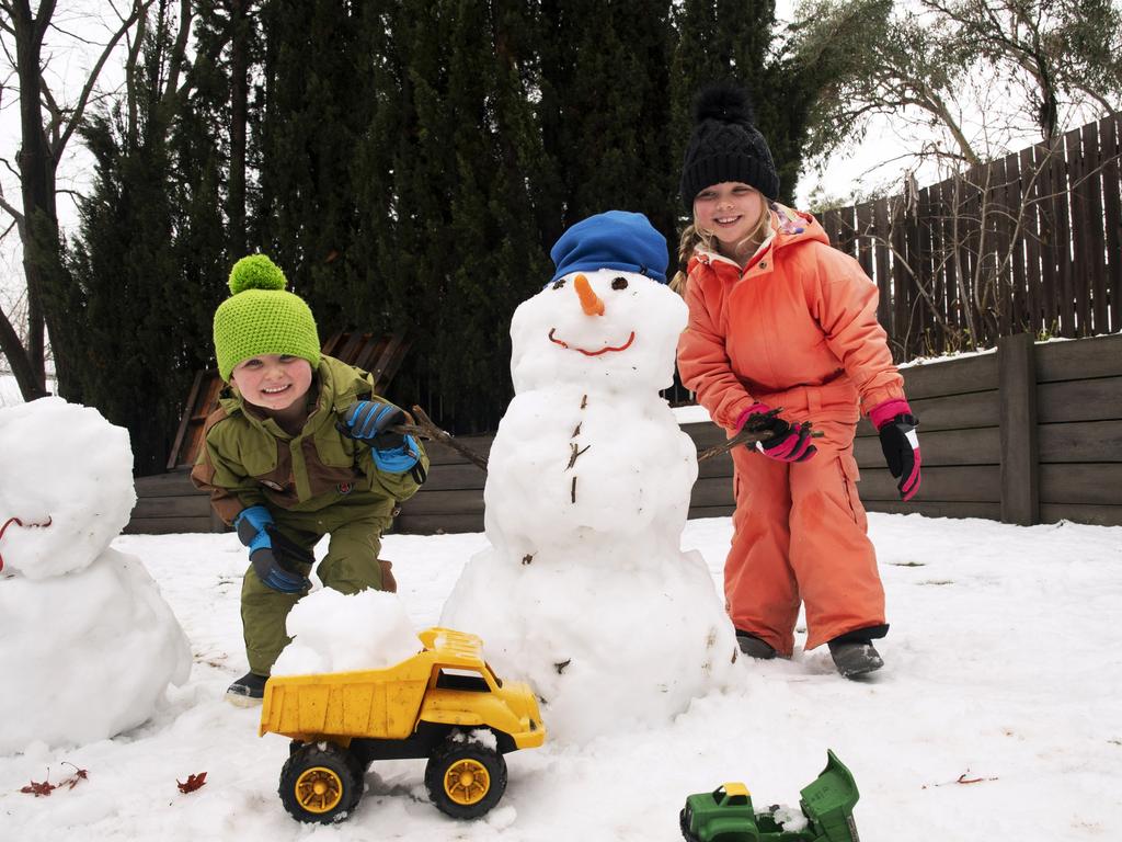 An unexpected snowfall in the town of Jindabyne was a welcome surprise for Jake and Ava Jungmayr at their East Jindabyne home. The kids said it was the first time they had seen snow in their yard. Picture: Steve Cuff .