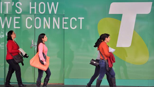 People pass a Telstra sign in Sydney on August 14, 2014. Australia's dominant telecom company posted a 14.3 percent jump in annual net profit to Aus$4.28 billion (US$3.98 billion) boosted by the sale of its Hong Kong mobile business CSL. AFP PHOTO/Peter PARKS