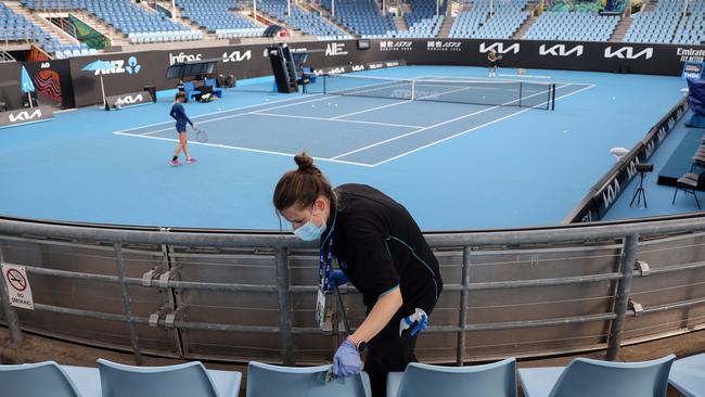 A worker cleans the seating areas during a warm up session at Melbourne Park in Melbourne during the Australian Open. Picture: AFP