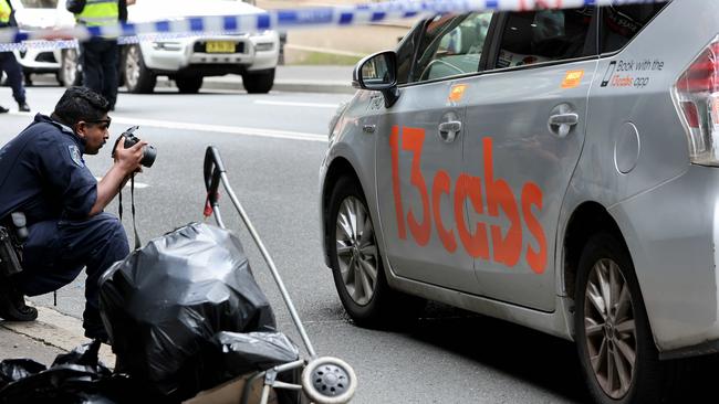 A police officer takes photos of the taxi involved in the incident. Picture: Damian Shaw