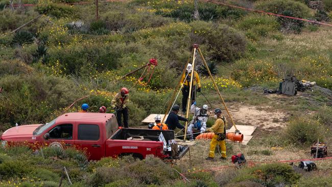 A rescue worker descends into a waterhole where human remains were found near La Bocana Beach, Santo Tomas delegation, in Ensenada, Baja California State, Mexico. Picture: Guillermo Arias / AFP