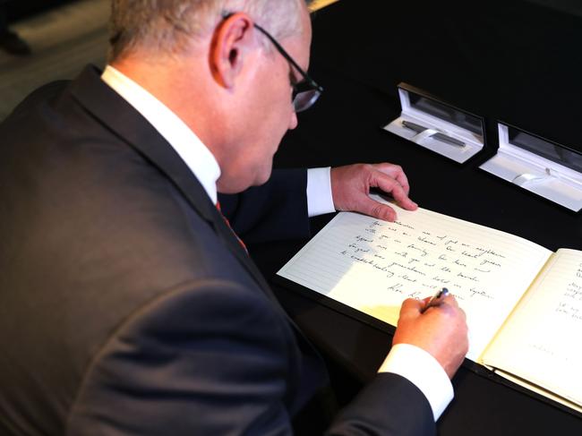 Prime Minister Scott Morrison writes a message in a condolence book at the New Zealand High Commission in Canberra.