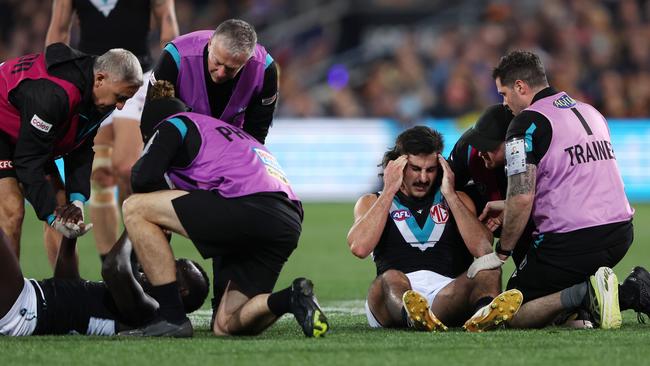 Port Adelaide teammates Aliir Aliir and Lachie Jones in the hands of trainers at Adelaide Oval. Picture: Getty Images.