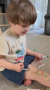 Kid colours on himself while colouring in book