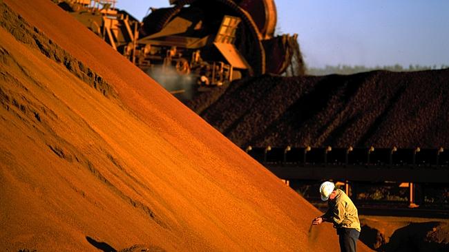 A worker inspecting iron ore stockpiles at the outback location of Marandoo owned by Rio Tinto.