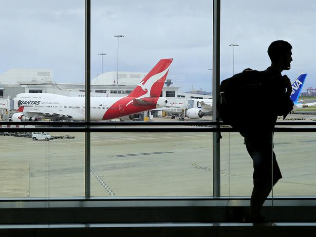 SYDNEY, AUSTRALIA - MARCH 10: A passenger walks past a Qantas jet at the International terminal at Sydney Airport on March 10, 2020 in Sydney, Australia. Qantas has cut almost a quarter of its international capacity for the next six months as travel demands fall due to fears over COVID-19. The airline today announced it was altering routes to London and would be parking eight of their 12 A380 aircraft. (Photo by Mark Evans/Getty Images)