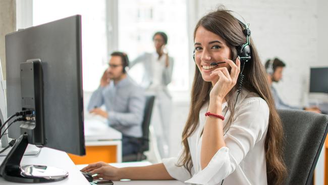 Young friendly operator woman agent with headsets working in a call centre.