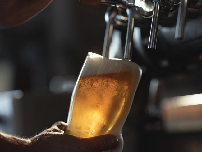 Fresh beer filling the glass directly from the tap. With extra foam spilling over glass.