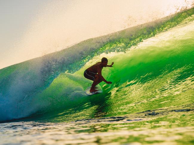 September 8, 2018. Bali, Indonesia. Surfer ride on barrel wave at warm sunset. Professional surfing in ocean, Bingin beach. Picture: iStock