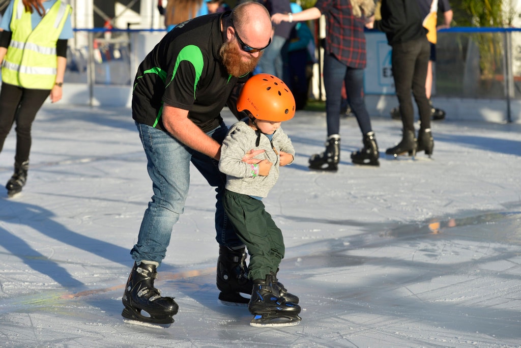 Josh Darcy helps son Seth learn to ice skate at Winter Wonderland in the Civic Square, Friday, June 22, 2018. Picture: Kevin Farmer