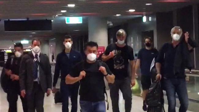 Serbia's Novak Djokovic, third from left, prepares to depart from Melbourne Airport on January 16 amid a vaccination row.