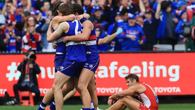 Bulldogs players celebrate as Josh Kennedy ponders another Grand Final loss. Picture: Toby Zerna