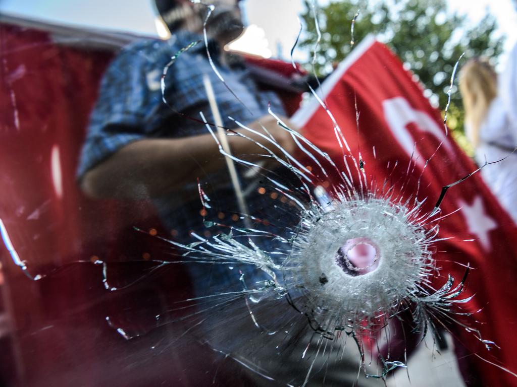 Demonstrators seen through a hole in hotel`s a window near Istanbul’s Taksim Square wave Turkish flags on July 24, 2016 during the first cross-party rally to condemn the coup attempt against President Recep Tayyip Erdogan. Picture: AFP PHOTO / OZAN KOSE