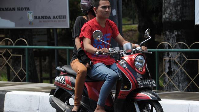 A man and a woman ride a motor bike in Banda Aceh on May 4, 2015.