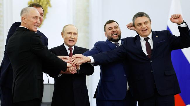 The Moscow-appointed heads of Kherson region Vladimir Saldo, left, and Zaporizhzhia region Yevgeny Balitsky, Vladimir Putin, Donetsk separatist leader Denis Pushilin and Lugansk separatist leader Leonid Pasechnik join hands after signing treaties formally annexing the four region. Picture: AFP.