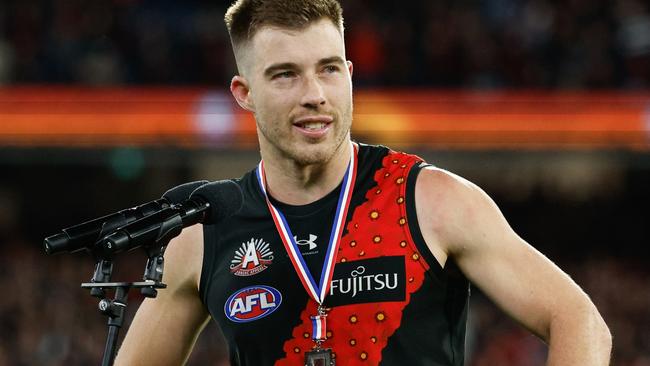 MELBOURNE, AUSTRALIA - APRIL 25: Zach Merrett of the Bombers receives the Anzac Day Medal during the 2024 AFL Round 07 match between the Essendon Bombers and the Collingwood Magpies at the Melbourne Cricket Ground on April 25, 2024 in Melbourne, Australia. (Photo by Dylan Burns/AFL Photos via Getty Images)