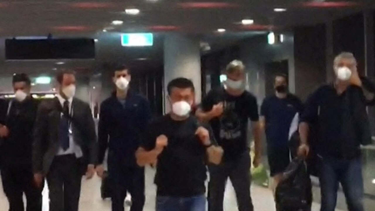 This screen grab taken from AFPTV shows Serbia's Novak Djokovic (3rd L) preparing to depart from Melbourne Airport in Melbourne on January 16, 2022, after losing a sensational legal battle over his coronavirus vaccination status with his dream of clinching a record 21st Grand Slam in tatters. (Photo by Mell CHUN / AFP) / -- IMAGE RESTRICTED TO EDITORIAL USE - STRICTLY NO COMMERCIAL USE