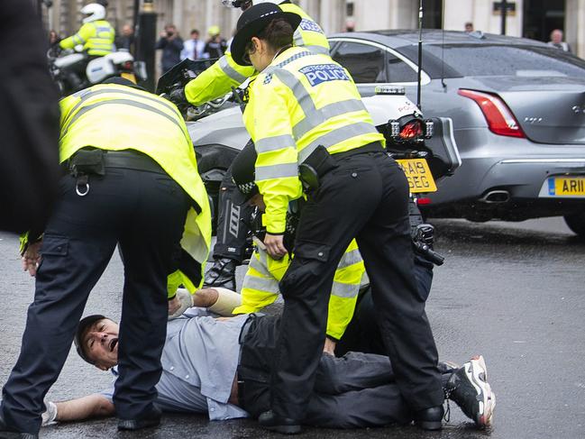 Police detain a man after running in front of Britain's Prime Minister Boris Johnson's car. Picture: AP