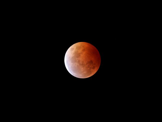 The moon photographed from Sandy Bay, NSW, as it turns red during the lunar eclipse. Picture: Luke Bowden