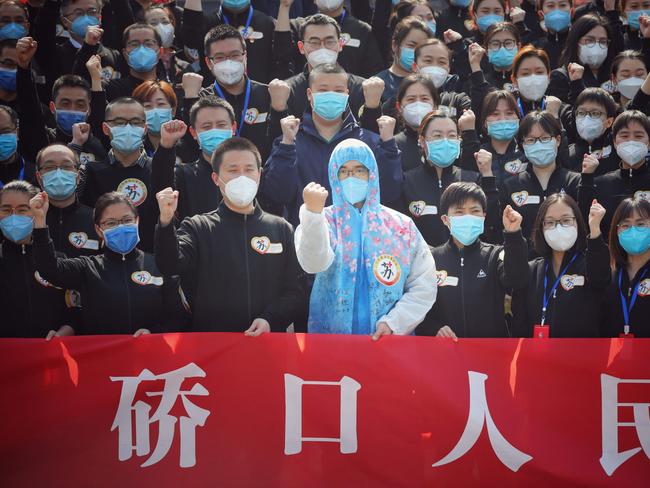 TOPSHOT - Members of a medical assistance team from Jiangsu province chant slogans at a ceremony marking their departure after helping with the COVID-19 coronavirus recovery effort, in Wuhan, in China's central Hubei province on March 19, 2020. - Medical teams from across China began leaving Wuhan this week after the number of new coronavirus infections dropped. China on March 19 reported no new domestic cases of the coronavirus for the first time since it started recording them in January, but recorded a spike in infections from abroad. (Photo by STR / AFP) / China OUT