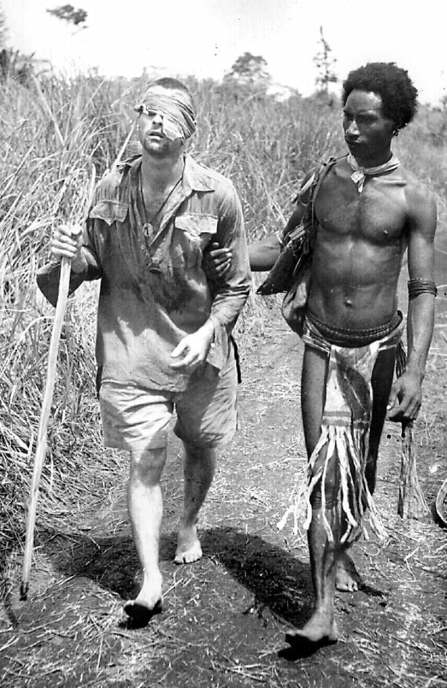 The story behind this remarkable image of New Guinea villager Raphael Oimbari leading a wounded soldier to safety has been revealed.