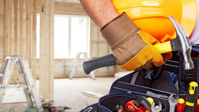 Builder handyman with construction tools. House renovation background.