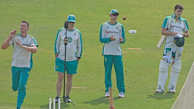 Ashton Agar and Pat Cummins watch on as Josh Hazlewood charges in at training.