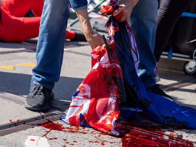 MELBOURNE, AUSTRALIA - SEPTEMBER 22: The Australian flag is cut up and has mock blood poured over it during a protest on September 22, 2022 in Melbourne, Australia. Indigenous groups have held "Abolish the Monarchy" rallies around Australia on Thursday to highlight the impact of British colonisation in Australia. Thursday 22 September was declared a one-off public holiday as a National Day of Mourning for Australia following Queen Elizabeth II's death. (Photo by Asanka Ratnayake/Getty Images)