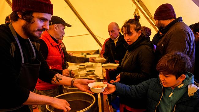 Volunteers hand out food for temporarily displaced persons prepared in a tent kitchen in Lviv.