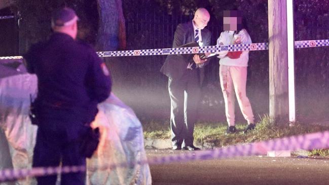 A woman covered in blood speaks with a detective the scene of the shooting in Panania Picture : Steve Tyson