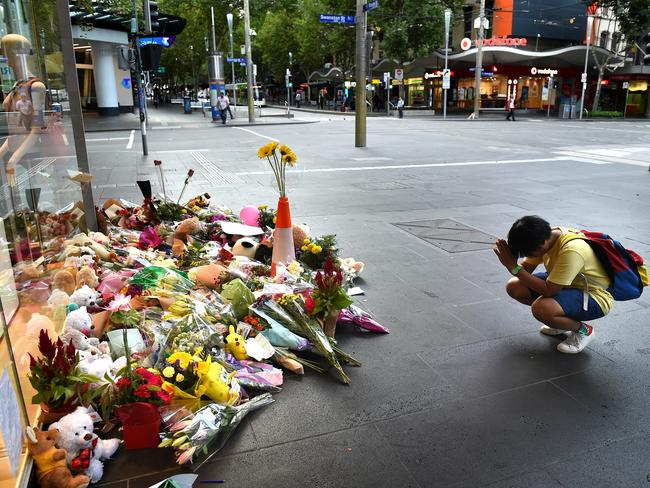 People pray and lay flowers on the corner of Swanston and Bourke streets. Picture: Nicole Garmston