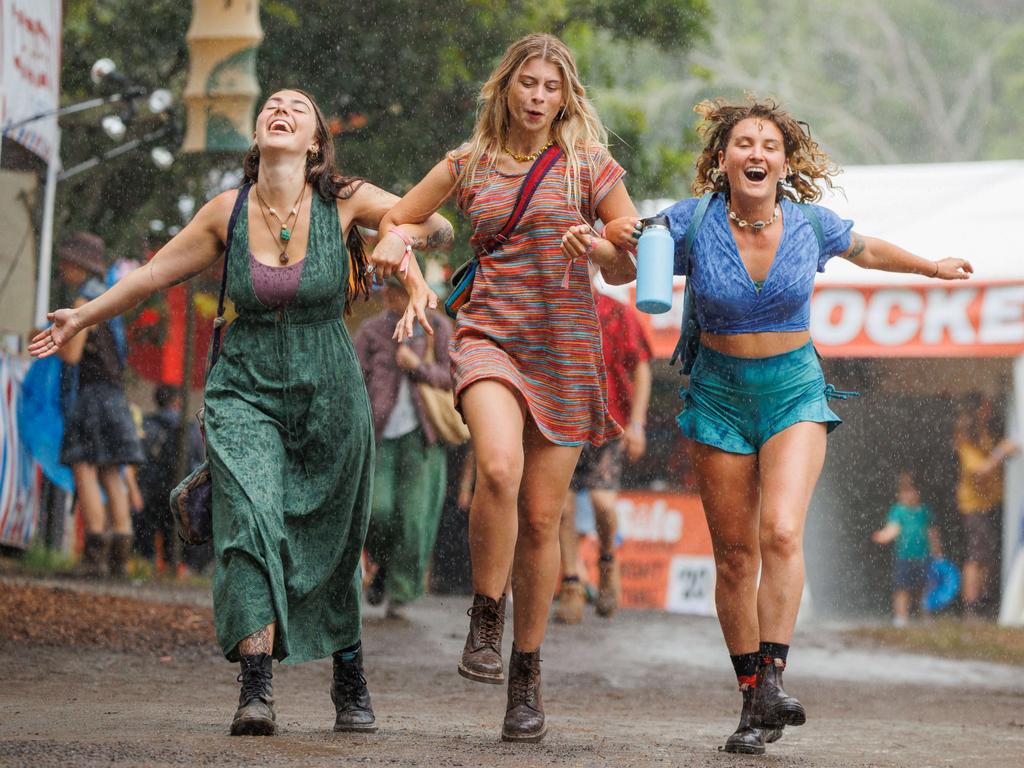 Friends let loose in the rain on day one of the Woodford Folk Festival. Picture: Lachie Millard