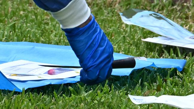 Police examine items on the front lawn of the home following the early morning incident. Picture: Lyndon Mechielsen/Courier Mail