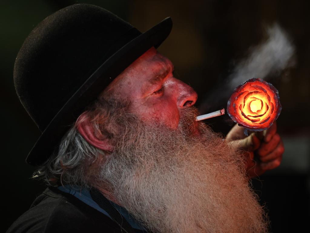 Brendan lights a cigarette with a red hot rose he is creating as a candle holder. Picture: David Caird