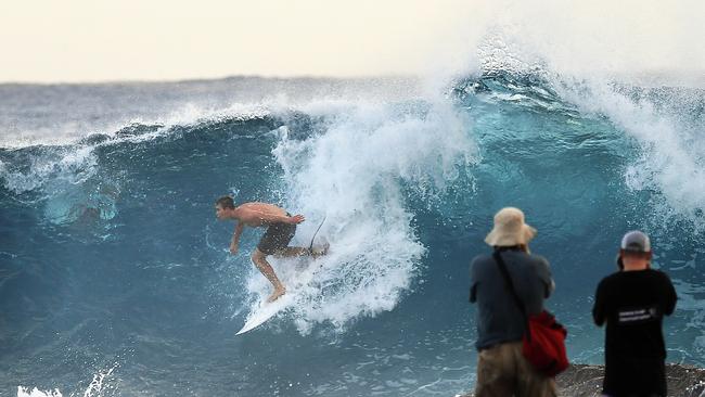 Photographers look on to a surfer at Snapper Rocks on the Gold Coast, Thursday February 21, 2019. Huge swells and high tides are set to pummelling southeast Queensland beaches over the coming days as Cyclone Oma tracks towards the Queensland coast. (AAP Image/Dave Hunt)