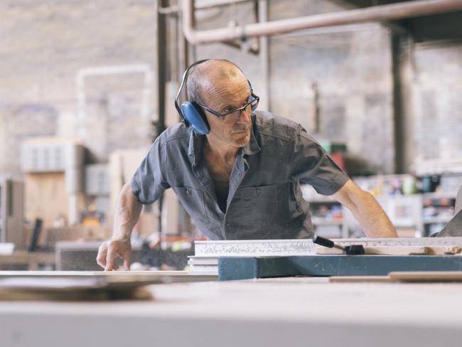 Young Carpenter using an electric saw to cut wood in a factory Picture: Istock