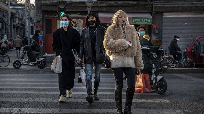 Women cross a road near closed shops in a traditional neighbourhood in Beijing, as some restrictions are relaxed. Picture: Getty Images