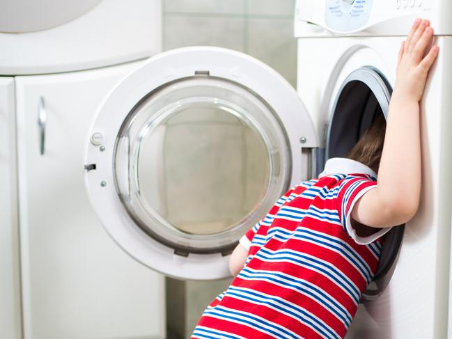 Little baby boy dangerously putting his head into washing machine - danger in bathroom